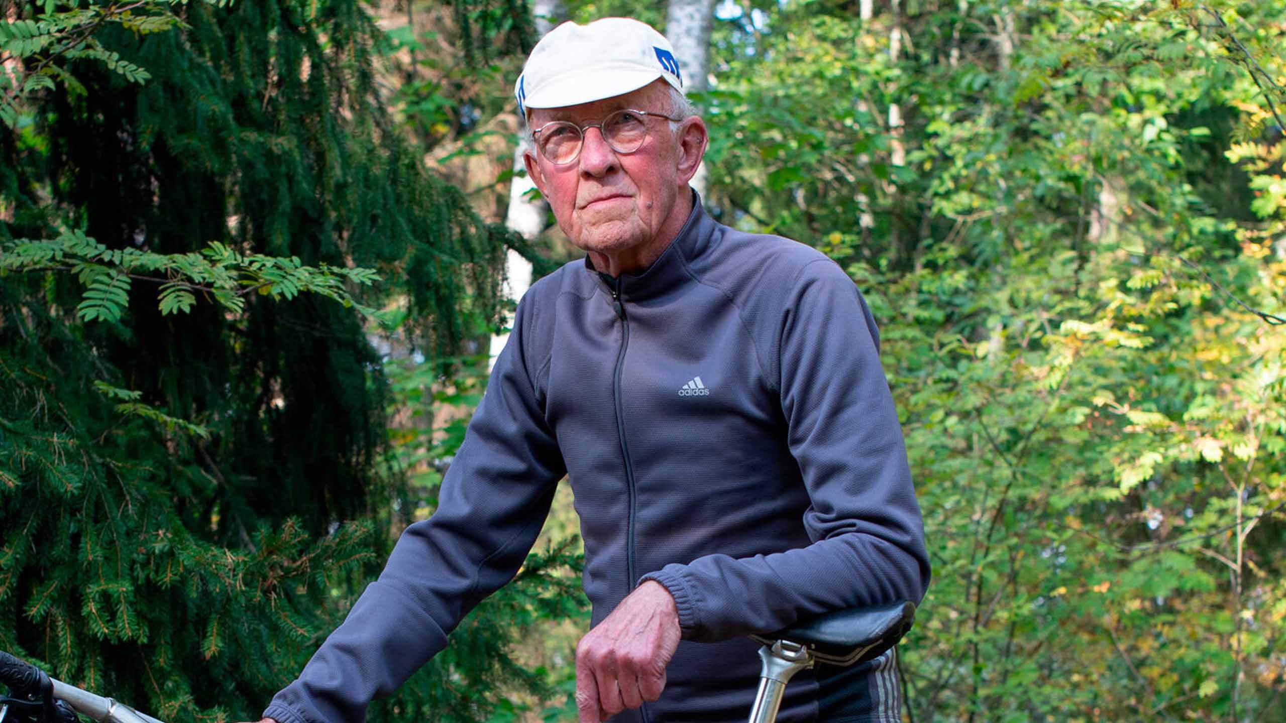 I&auml;k&auml;s mies seisoo ulkona ja nojaa rentona polkupy&ouml;r&auml;&auml;ns&auml;